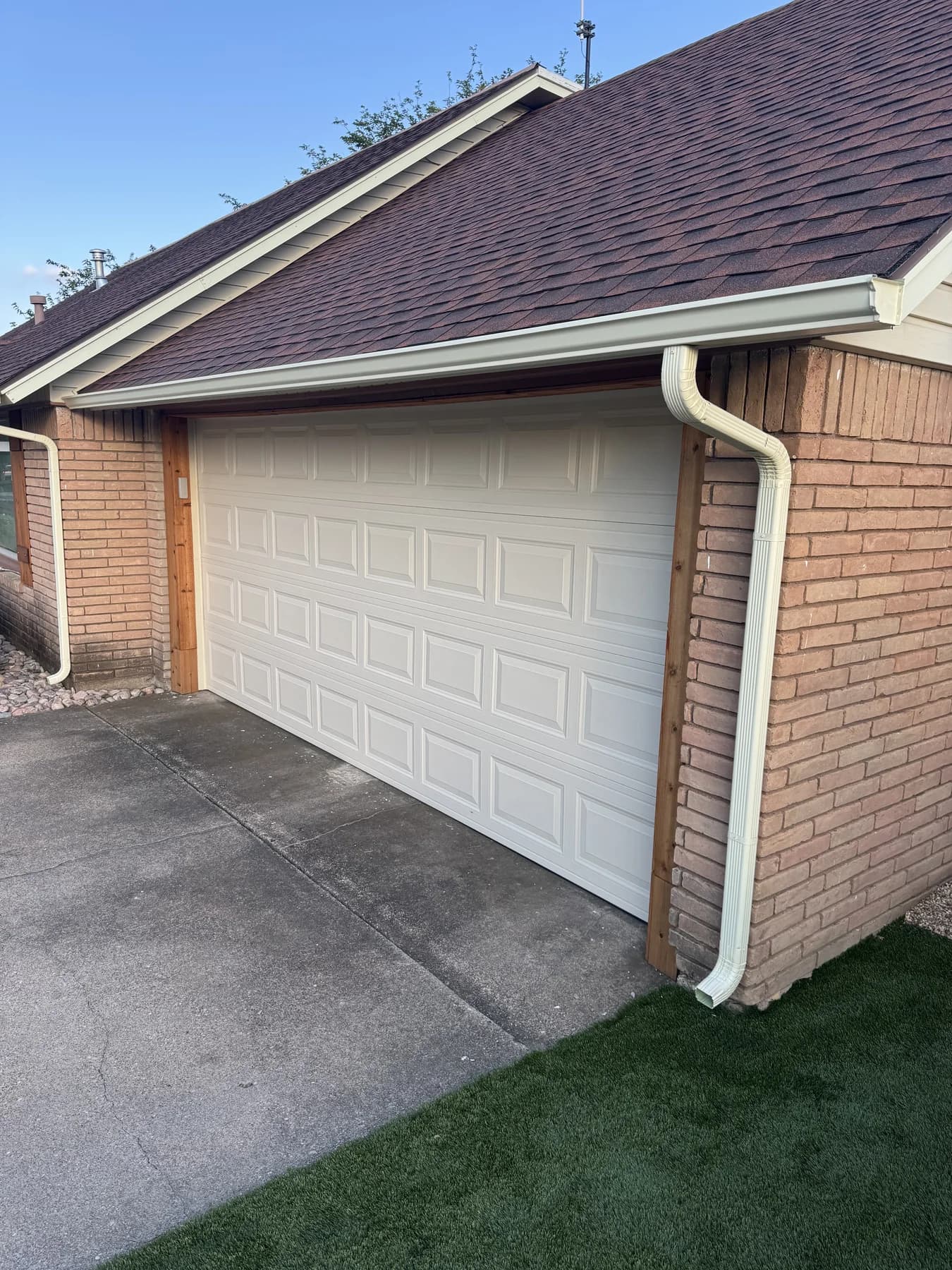 White seamless gutter and downspout installed above a garage