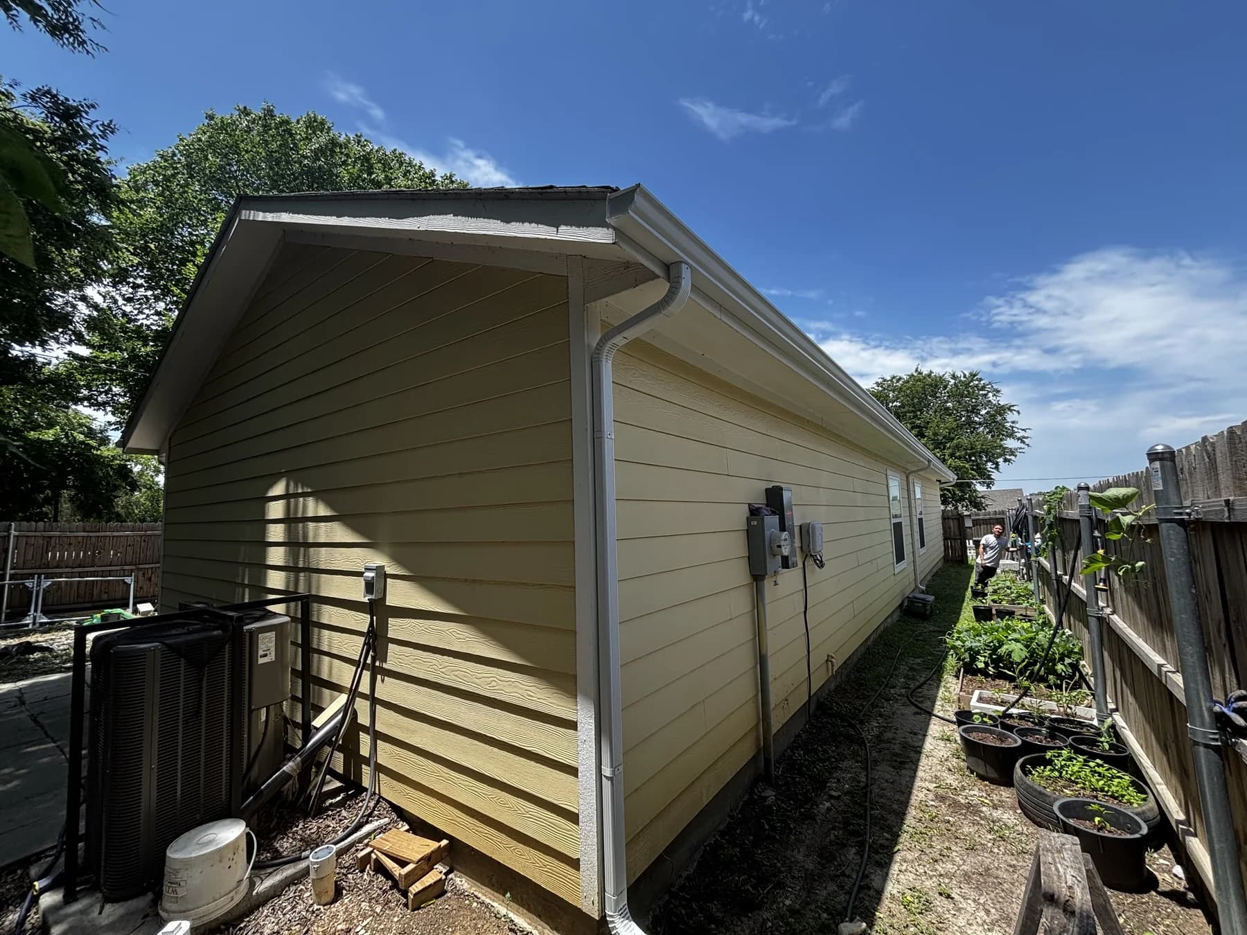 White gutter and downspout installed along a residential side wall